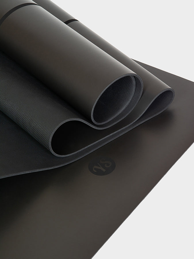 Black yoga mat with a brand logo on a light gray background